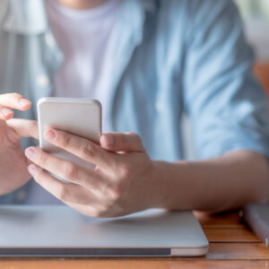 male hand text messaging on smartphone in workspace